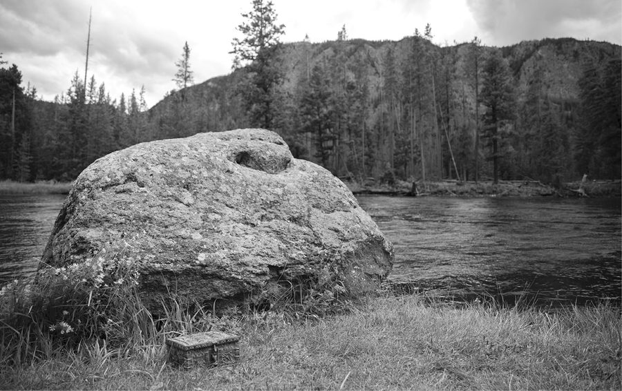 Large river boulder with a hollow like an eye, small chest in the grass